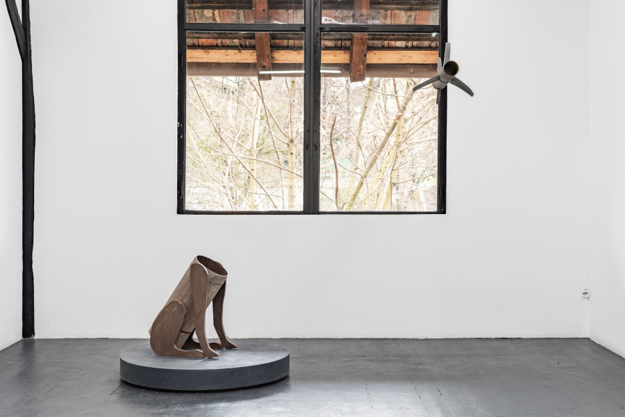 Left: Sam Porritt, Blind Obedience, 2024, Acrylic Paint, Cardboard Tubing, Chipboard, Glass Powder Screws, Steel, 60 x 50 x 30 cm Plinth: 12.5 x 95.5 cm. Right: Sam Porritt, Product of Its Environment, 2022, Acrylic Paint, Cardboard Tube, Screws, Steel Band, Wire, Wood, 33 x 77 cm. Photo: Kilian Bannwart